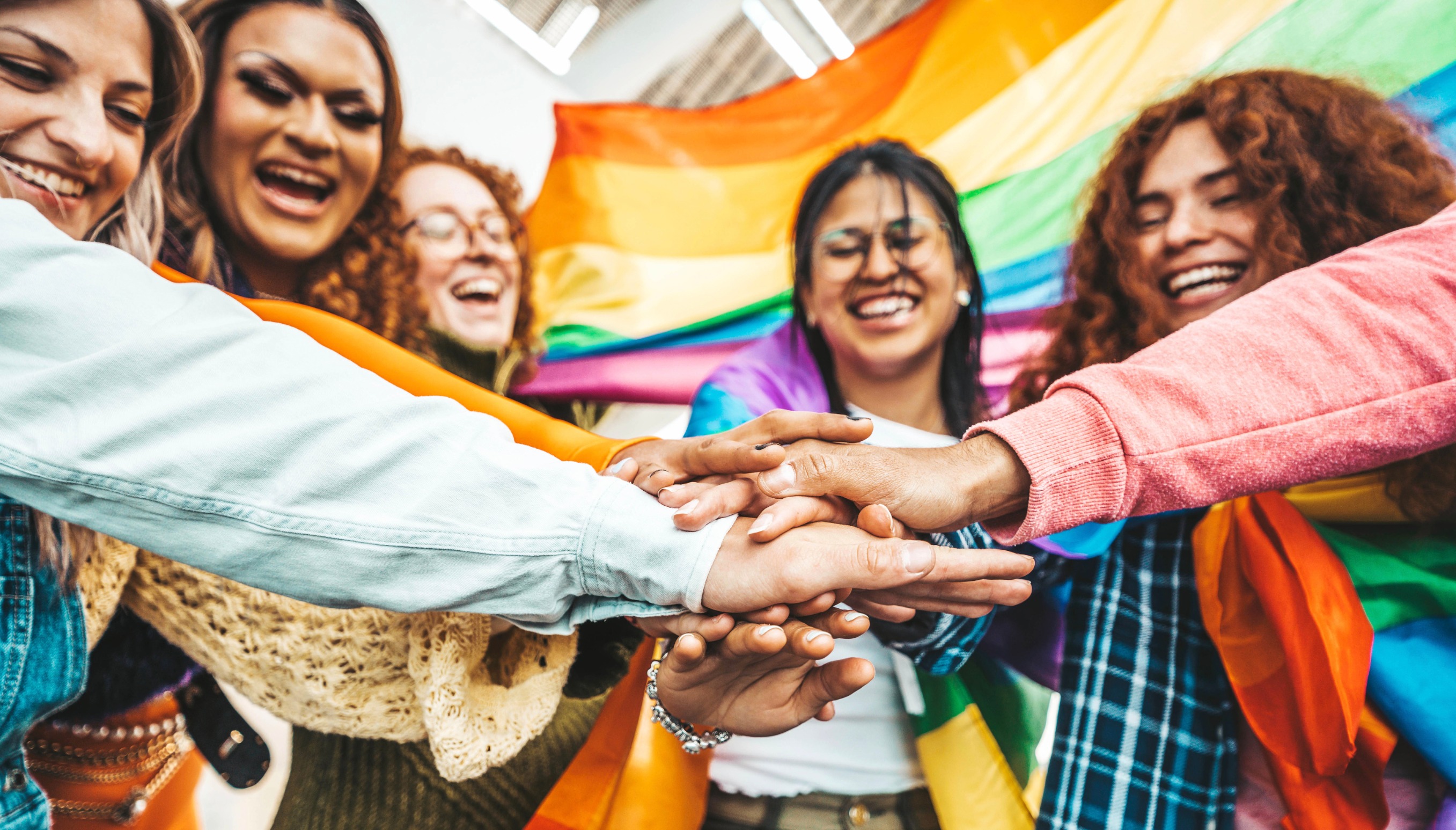 group of youth holding hands rainbow flag