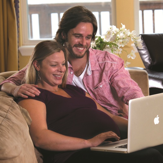 Pregnant couple looking at laptop