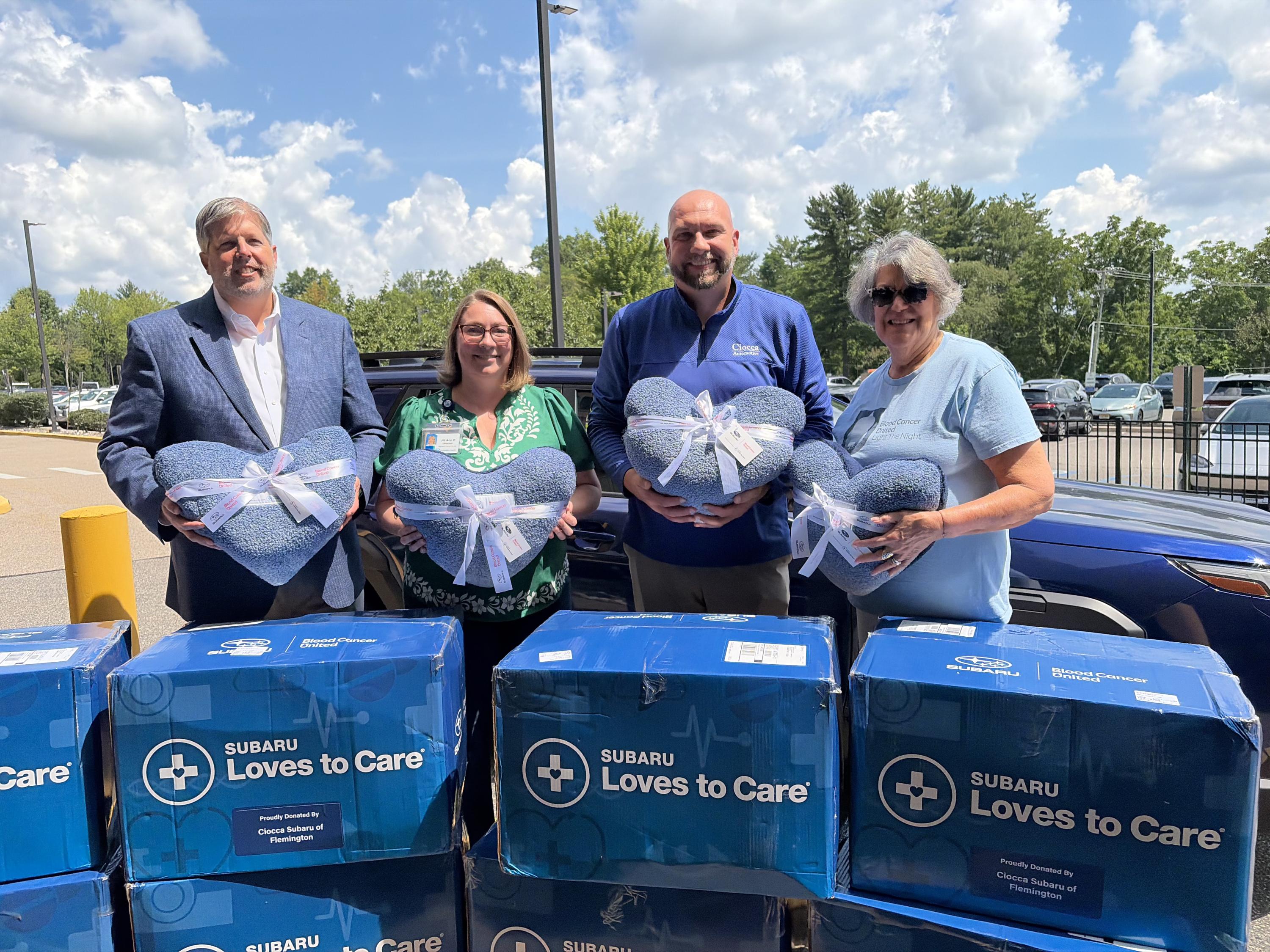 A group gathered with with a donation of heart shaped blankets for HRCC patients.
