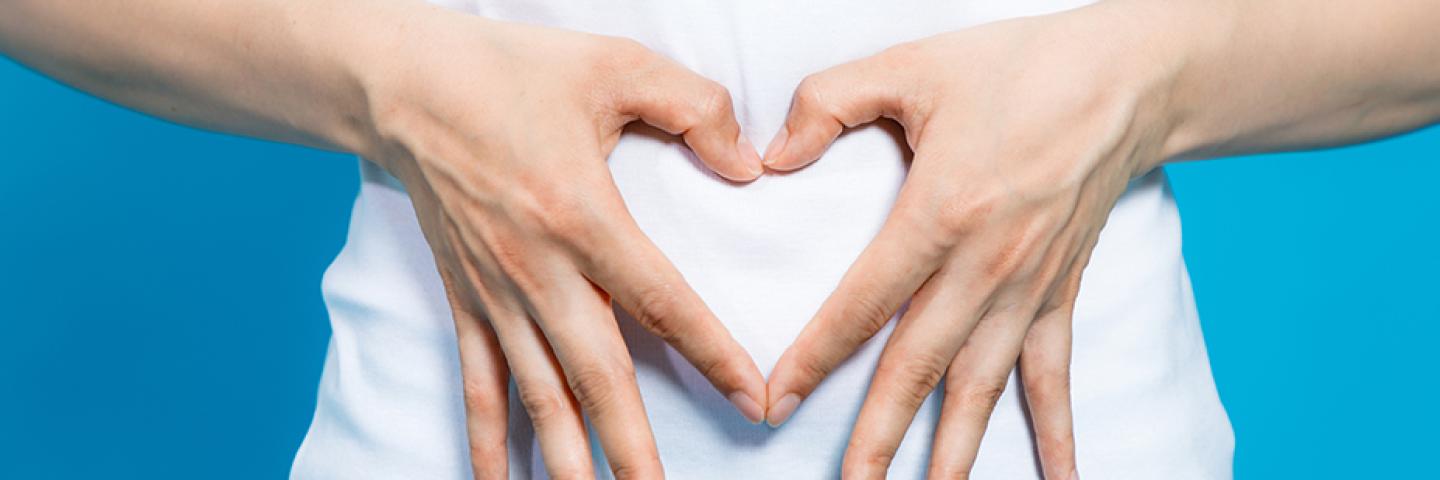 Person making a heart with their hands on their stomach