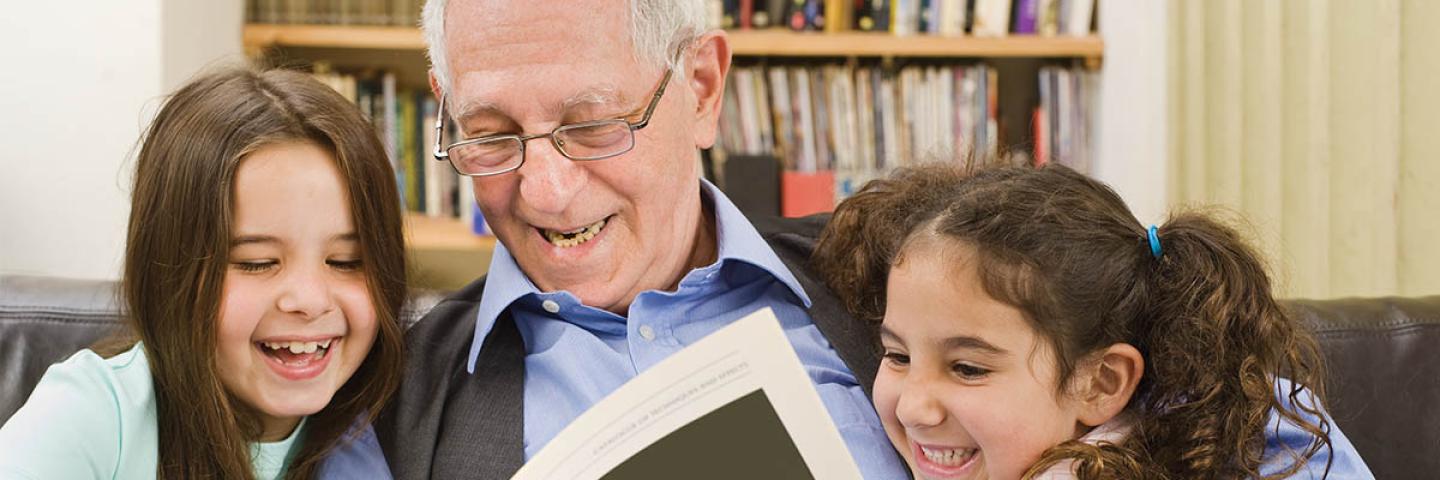 Grandfather reading to granddaughters 