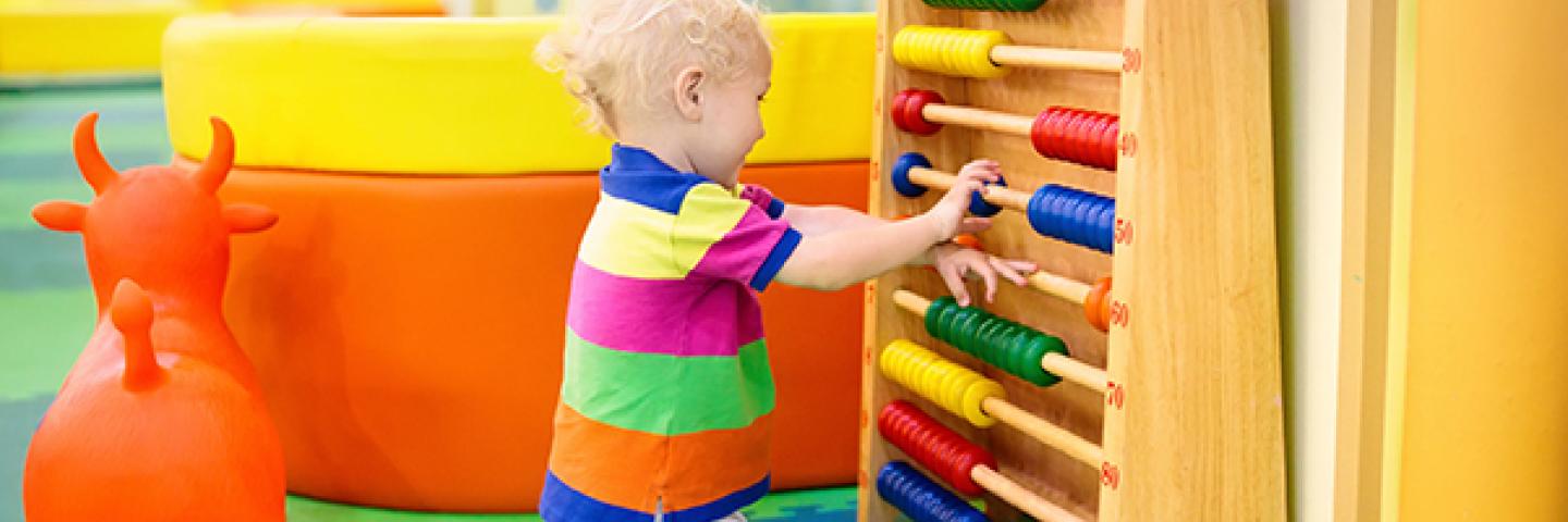 Young boy playing with wooden abacus