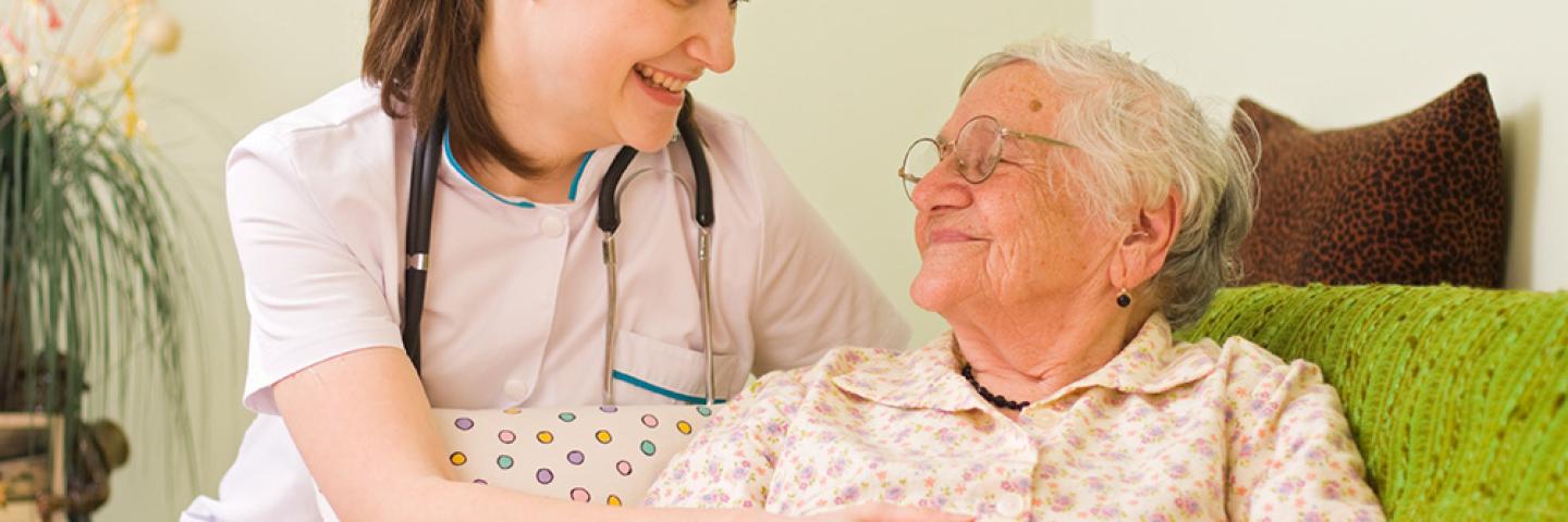 Young female nurse smiling at elderly female patient