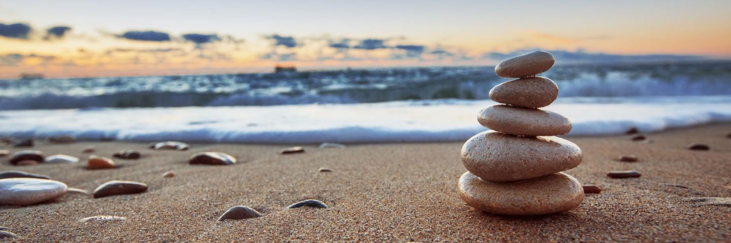 small pile of stones on sandy beach at sunset