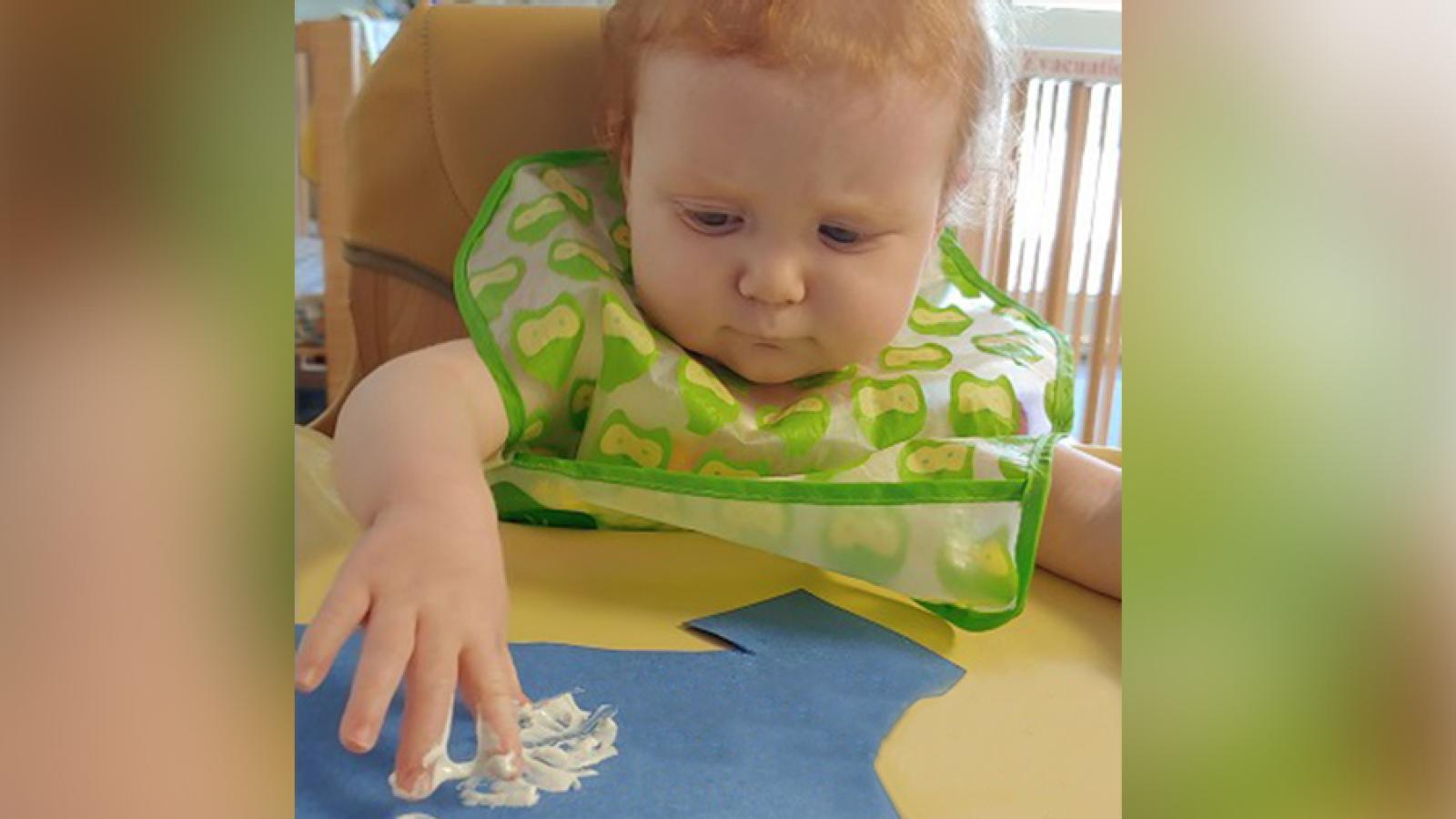 An infant finger paints.