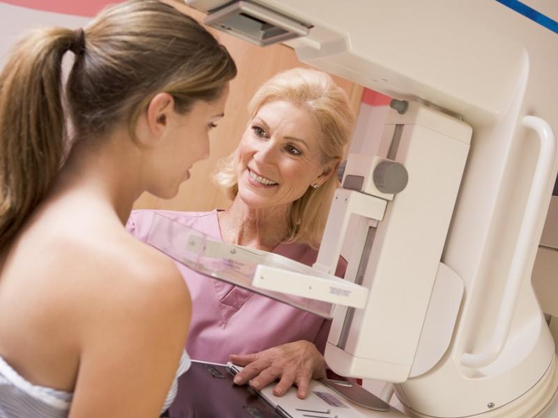 Women standing with technician at mammogram machine