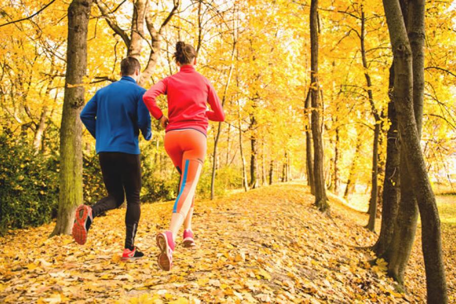 man and woman running through fall trees