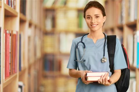 Student holding books wearing medical scrubs