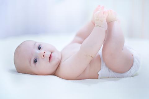 Photo of Smiling baby playing with feet