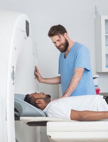 Male tech talking to patient in imaging machine prior to test