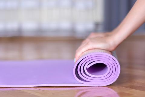 Photo of a female rolling up a yoga mat 
